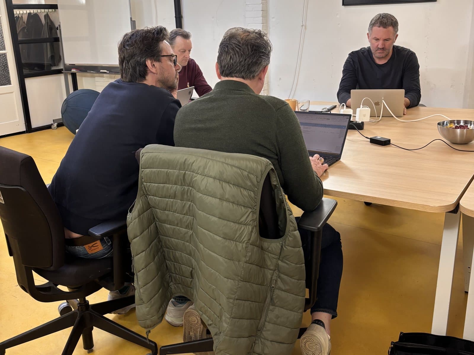 Deelnemers werken aan een tafel aan hun eigen taak met AI